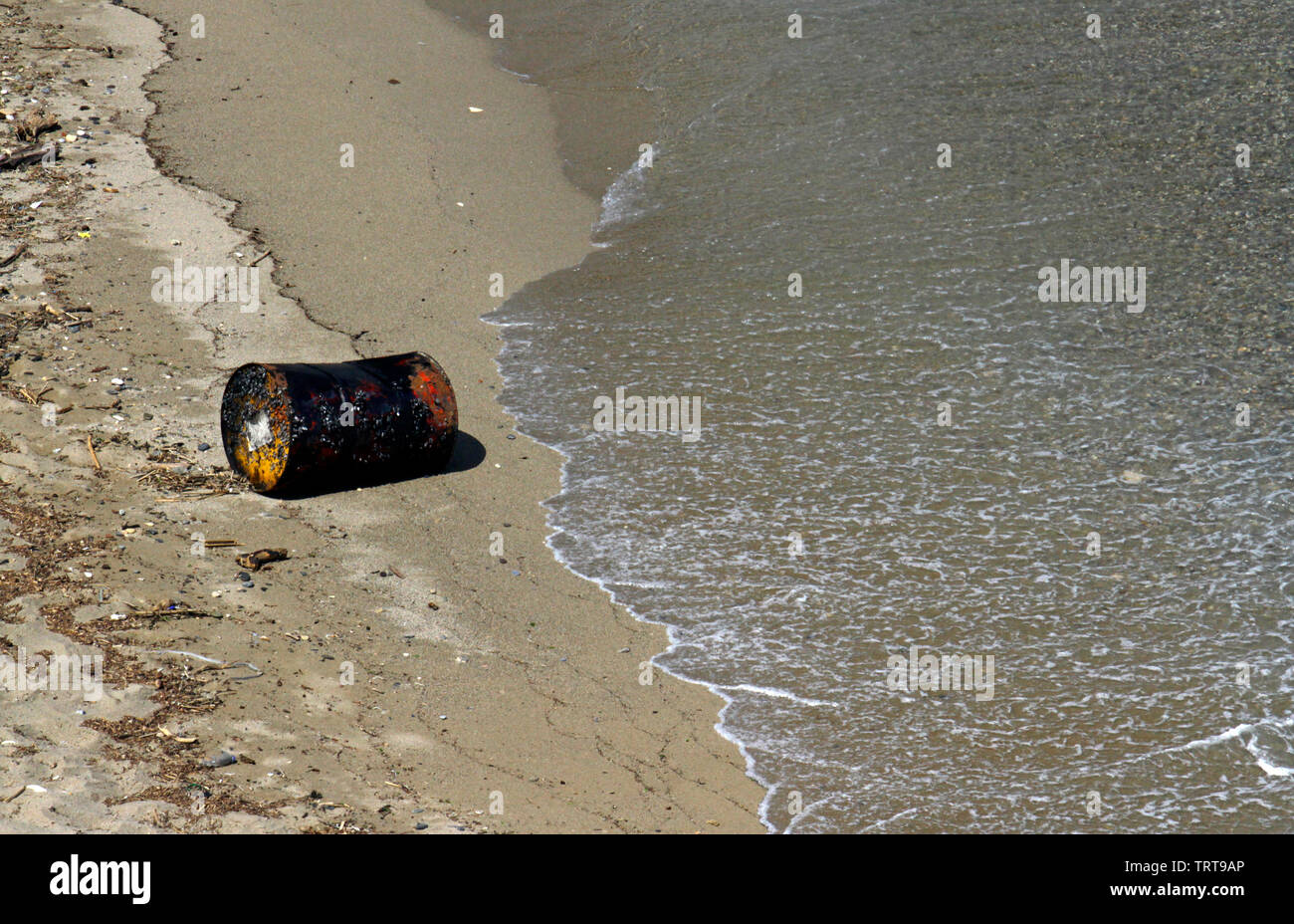 Ocean pollution: Old rusty oil barrel washed onto a beach Stock Photo