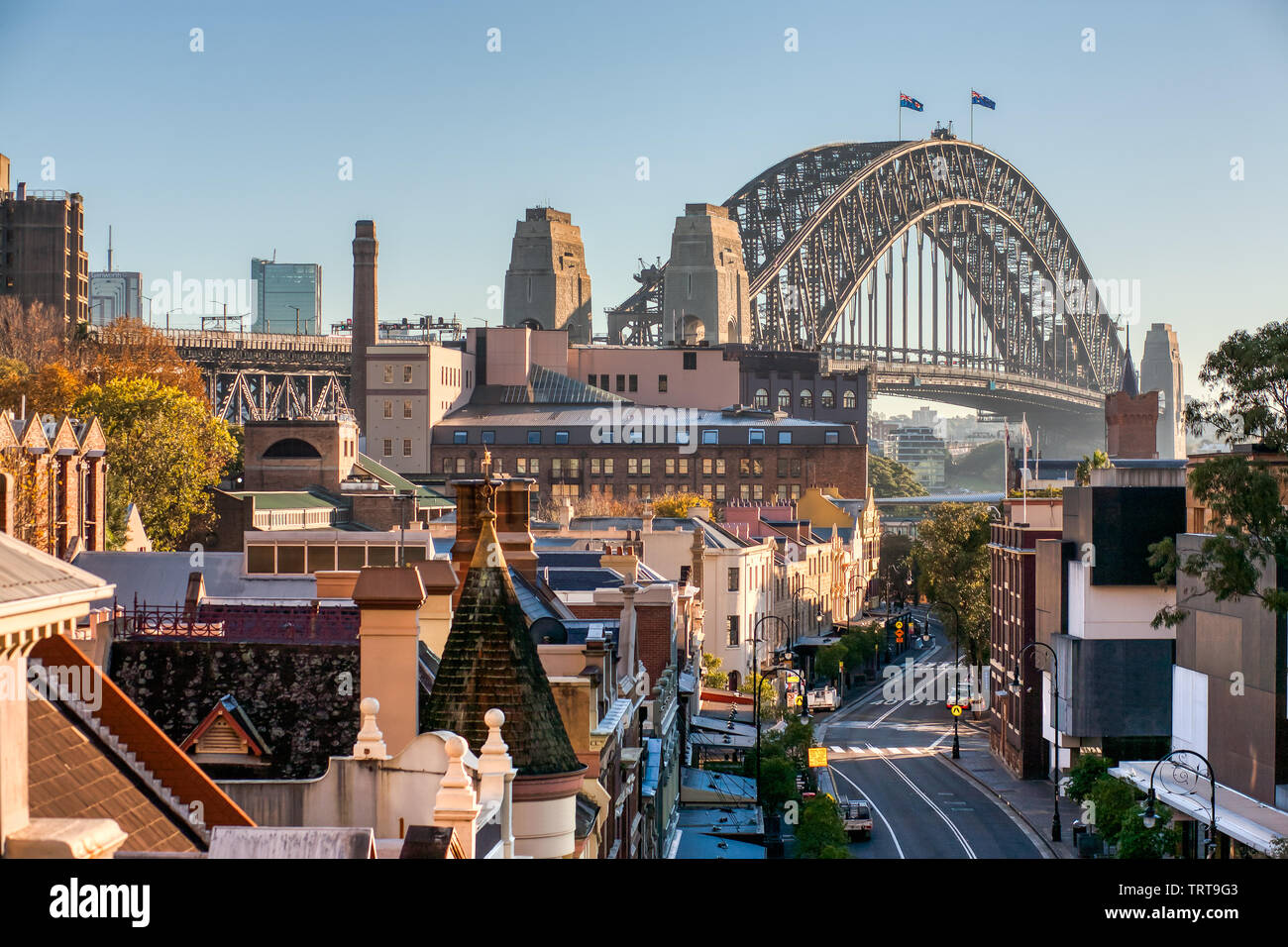 The Rocks, Sydney, George Street, Sydney Harbour Bridge and buildings with blue sky. Famous Historic Downtown street. Sunny Morning. Stock Photo