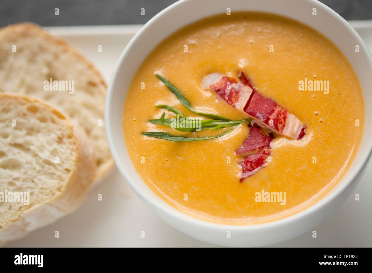 A bowl of the famous dish of lobster bisque, a soup with French origins made from the shells and meat of a lobster and includes various vegetables, he Stock Photo