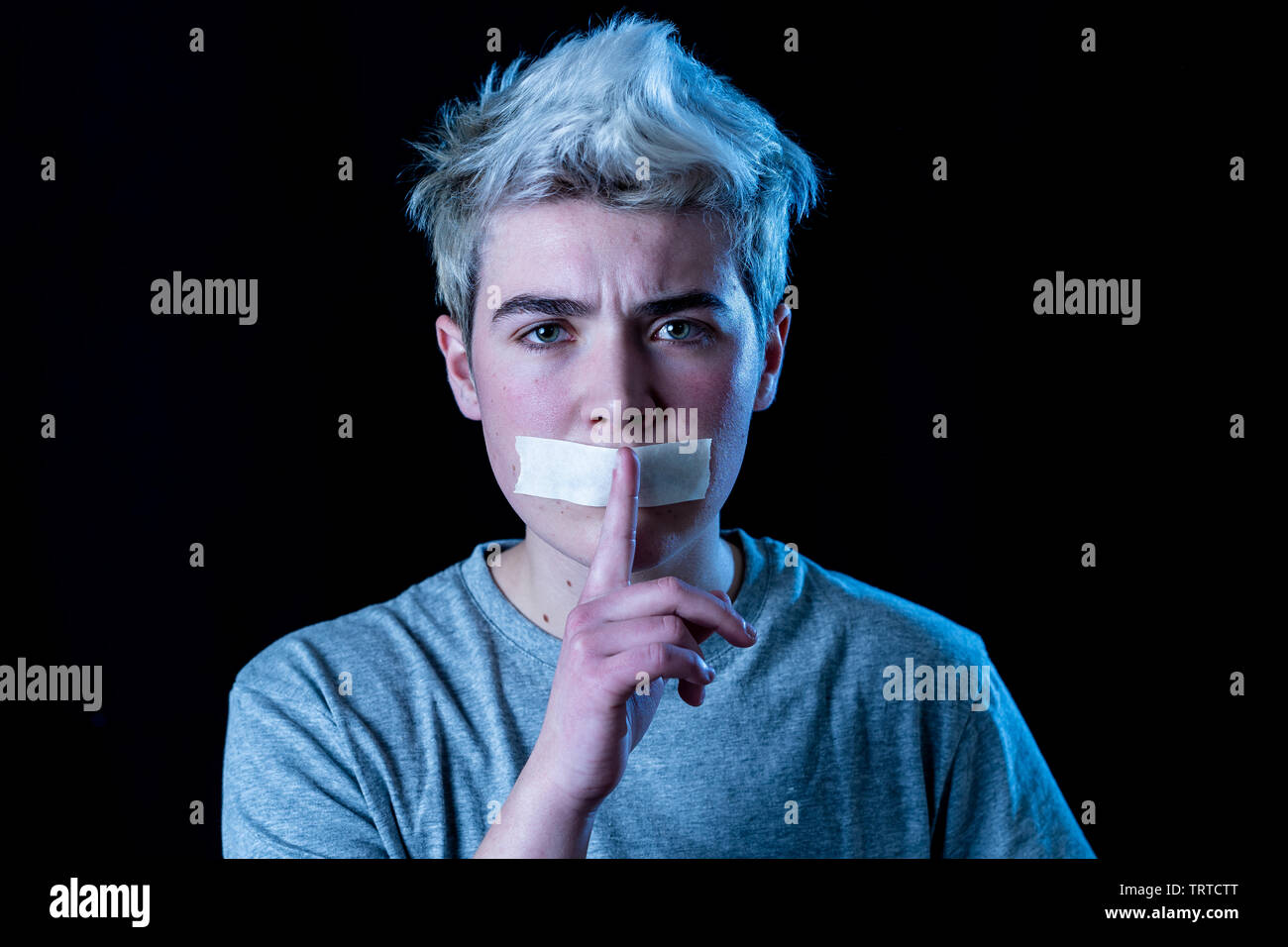 Attractive scared transgender boy with taped mouth in silence not able to talk about his gender identity In Censorship Taboo and intolerance Concept. Stock Photo