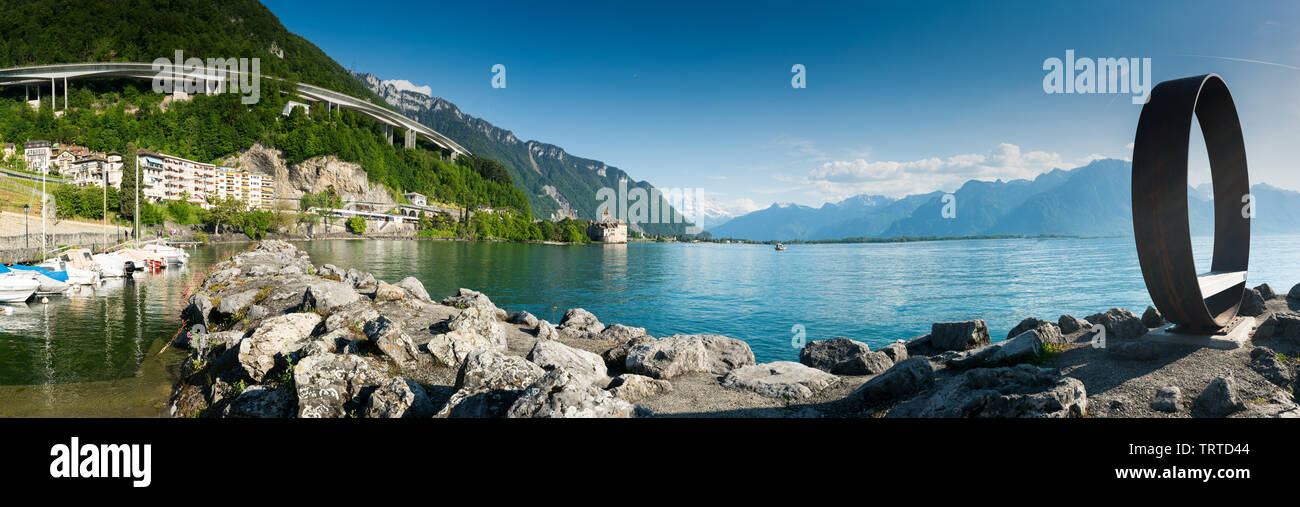 Territet, VD / Switzerland - 31 May 2019: panorama landscape of Lake Geneva with Chillon Castle and Territet Harbor and sculpture and motorway Stock Photo