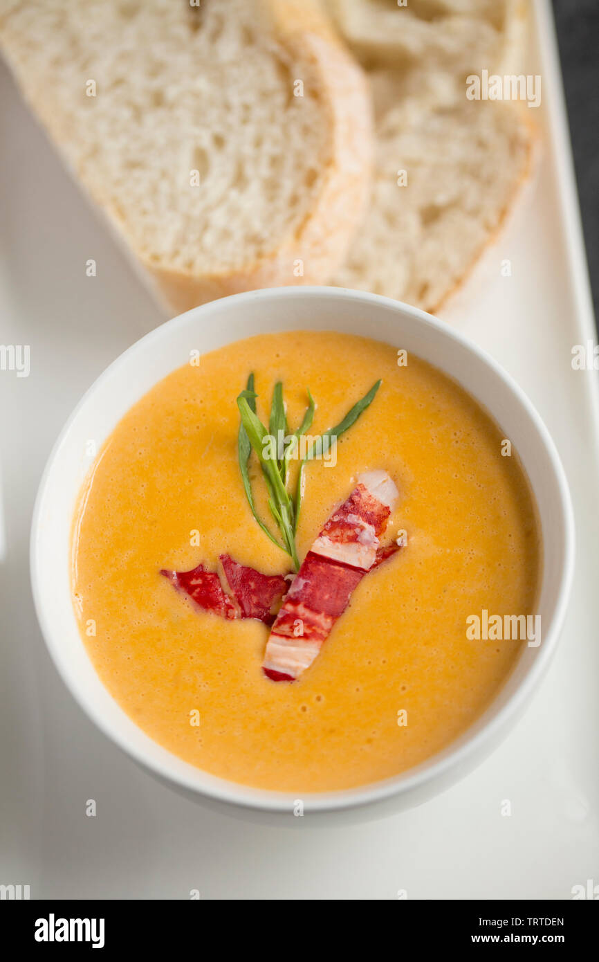 A bowl of the famous dish of lobster bisque, a soup with French origins made from the shells and meat of a lobster and includes various vegetables, he Stock Photo