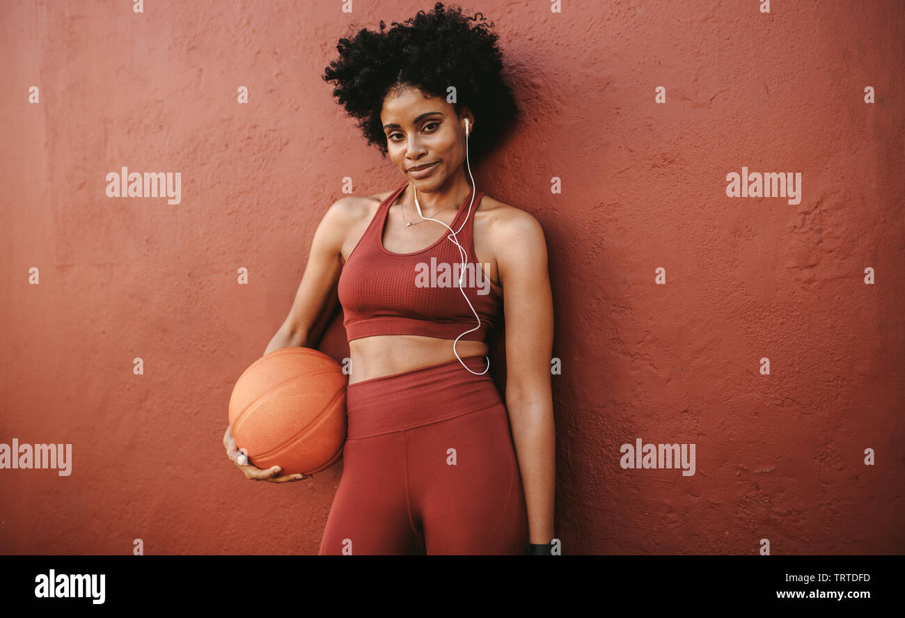 Fitness woman relaxing after workout standing with a basketball. Woman in  fitness wear relaxing after basket ball practice Stock Photo - Alamy