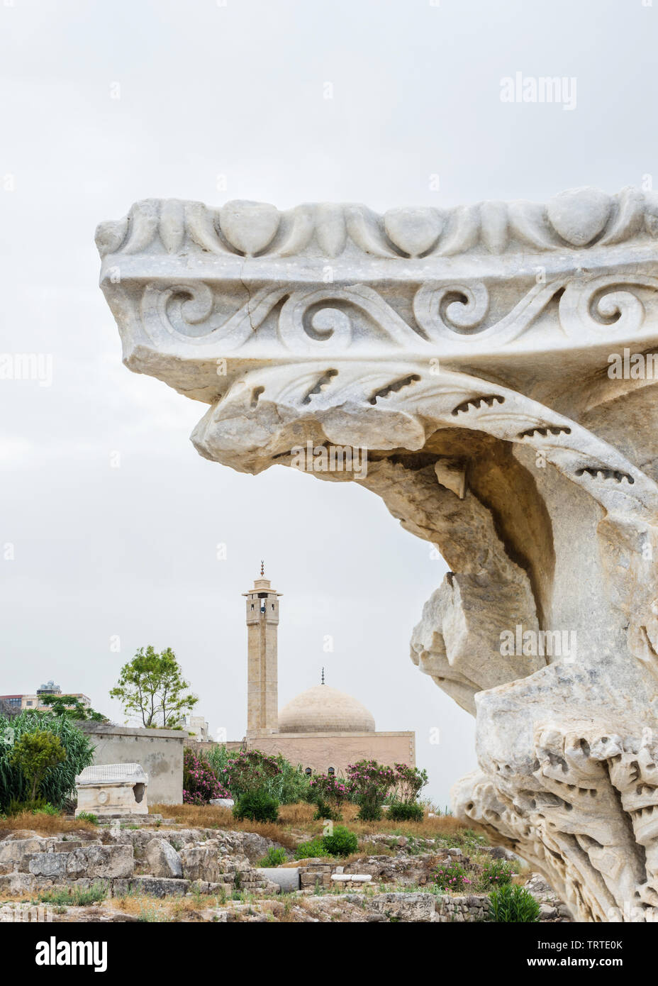 Roman column capital framing a mosque and an old sarcophagus, Al Mina archaeological site, Tyre, Lebanon Stock Photo