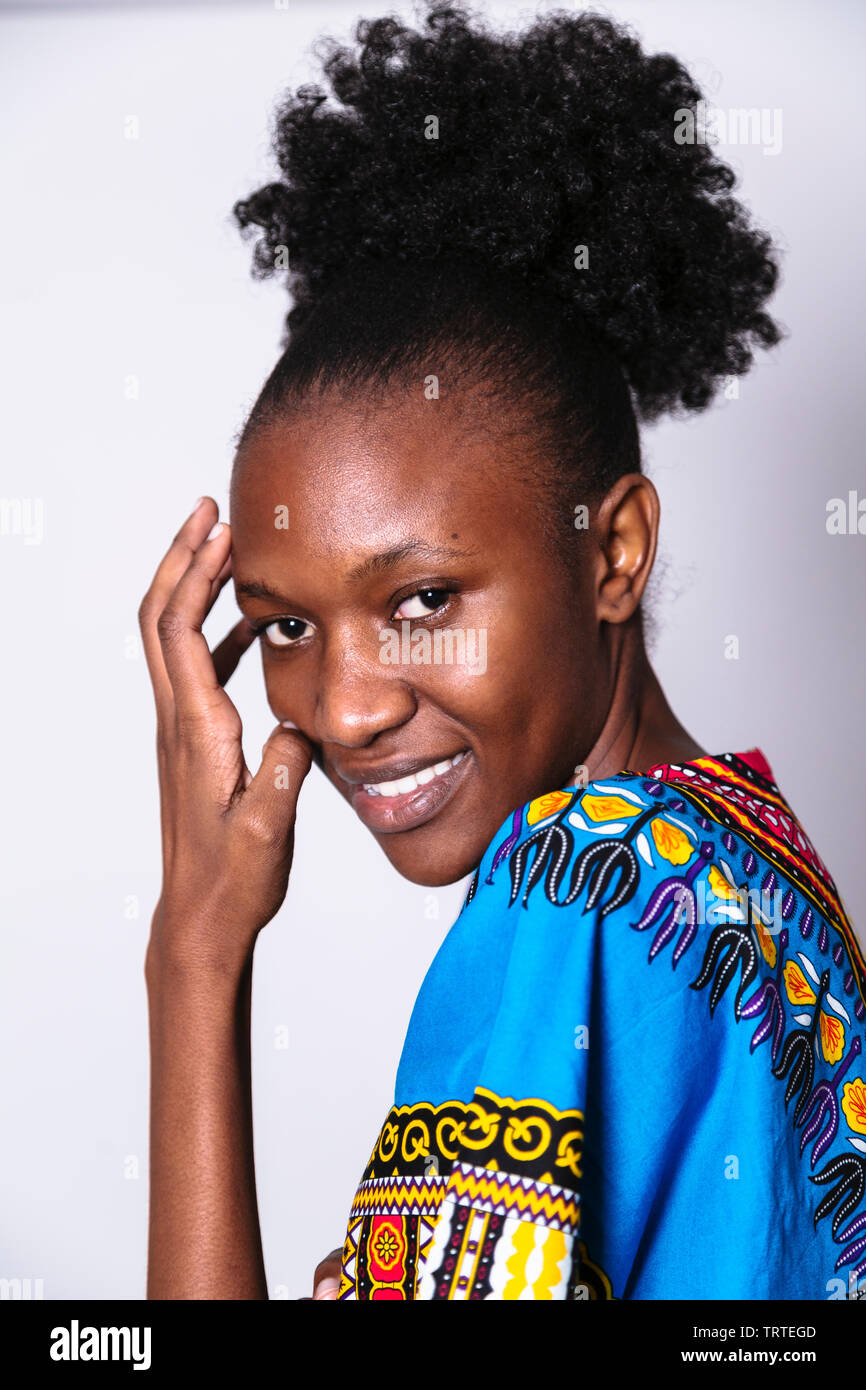 Young African Woman In Blue Dress With Pattern Is Half Turned And Smiling Stock Photo Alamy