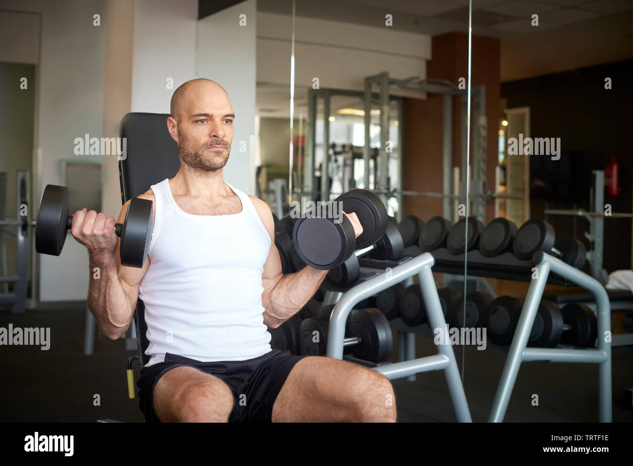 Closeup of man in the gym using barbells and doing dumbbell exercises