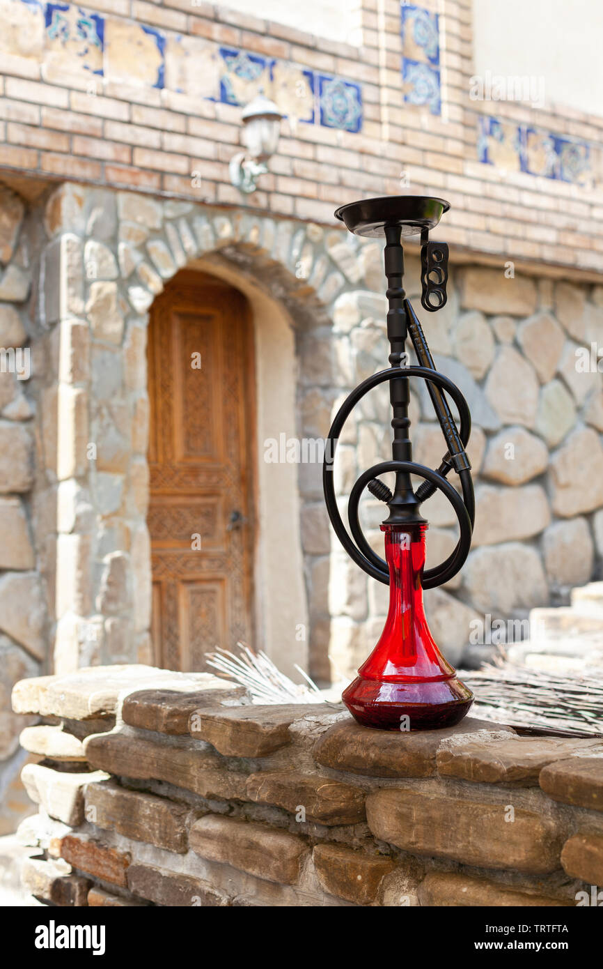 Black hookah with ruby bulb in authentic oriental antique cafe, outdoor. Front view, full length