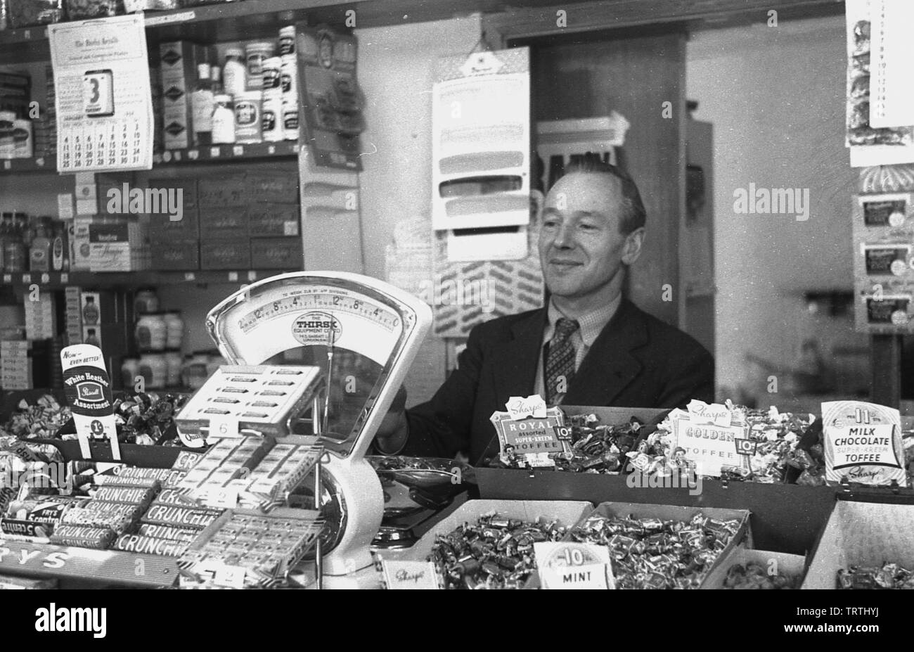 1950s, historical picture showing a male sweet shop owner behind the counter, England, UK. Stock Photo