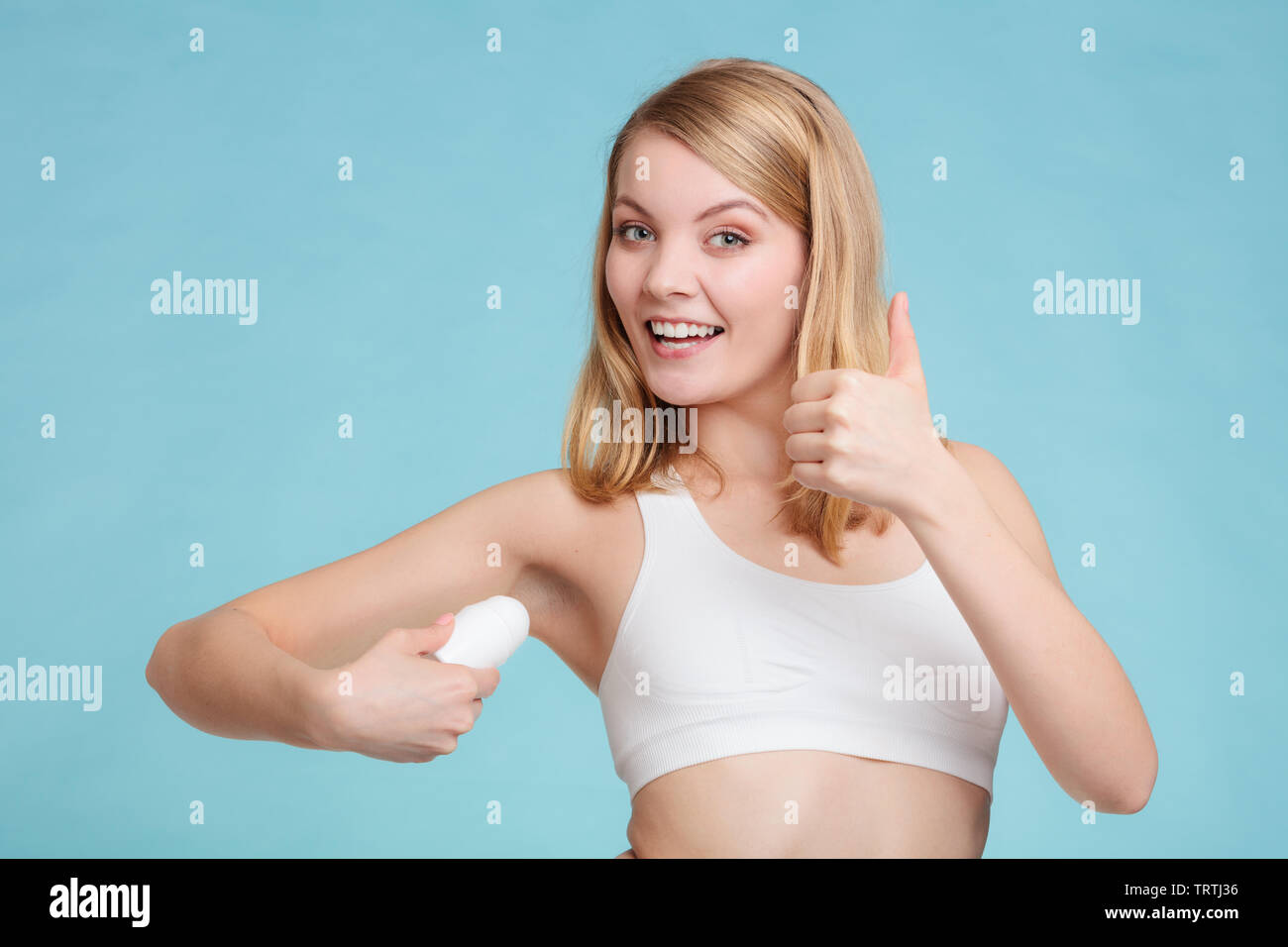 Daily skin care and hygiene. Girl applying stick deodorant in armpit. Young  woman putting antiperspirant in underarms on blue Stock Photo - Alamy