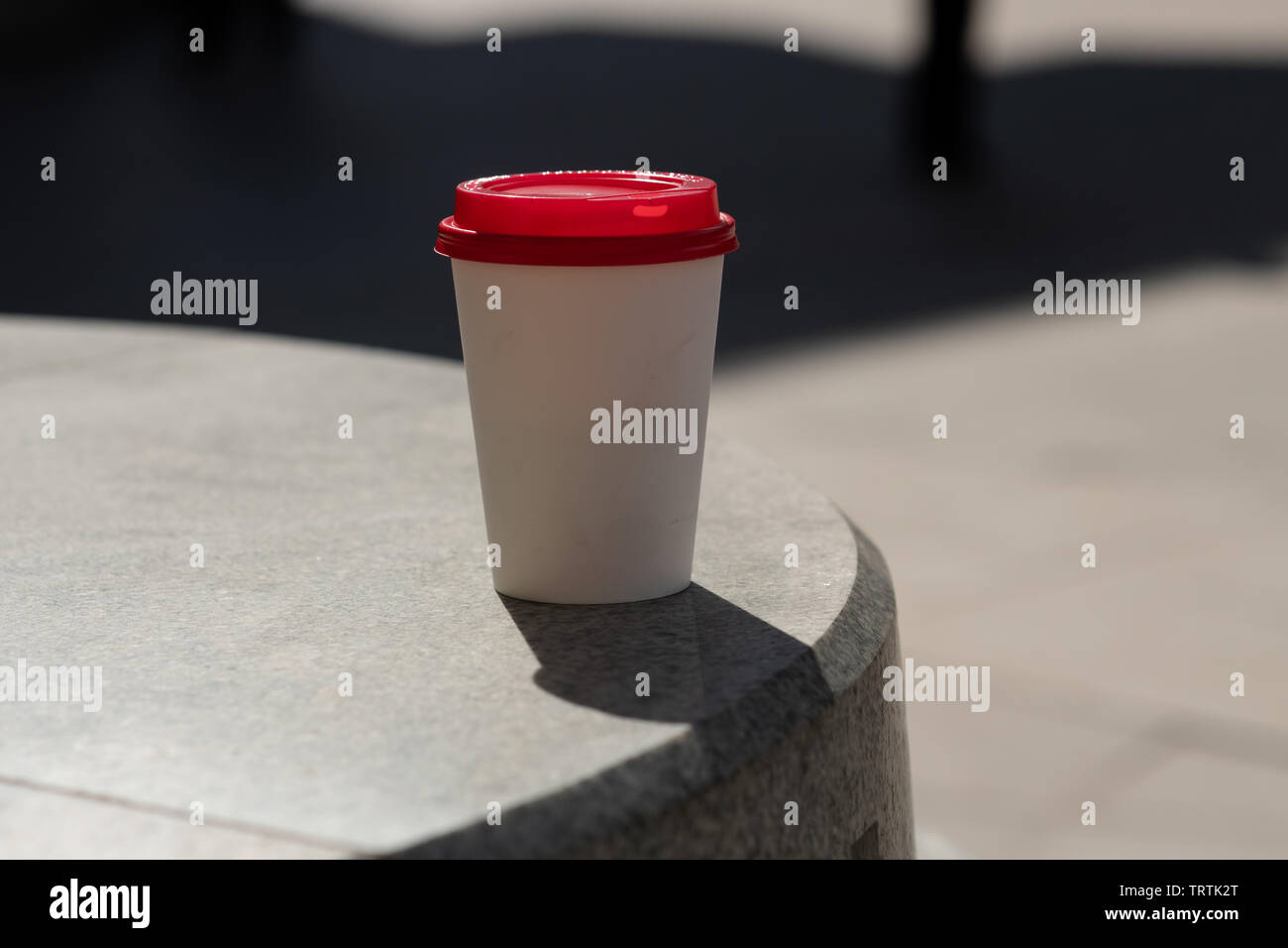 left on the street disposable white Cup of coffee on the stone surface. The theme of garbage in the city. Stock Photo