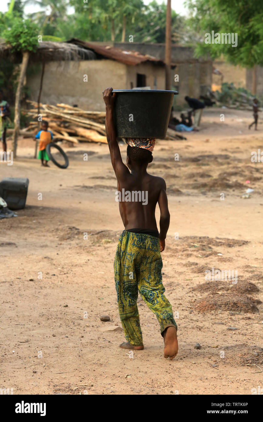 Enfant Togolais portant une bassine d'eau. Datcha Attikpayé. Togo. Afrique de l'Ouest. Stock Photo