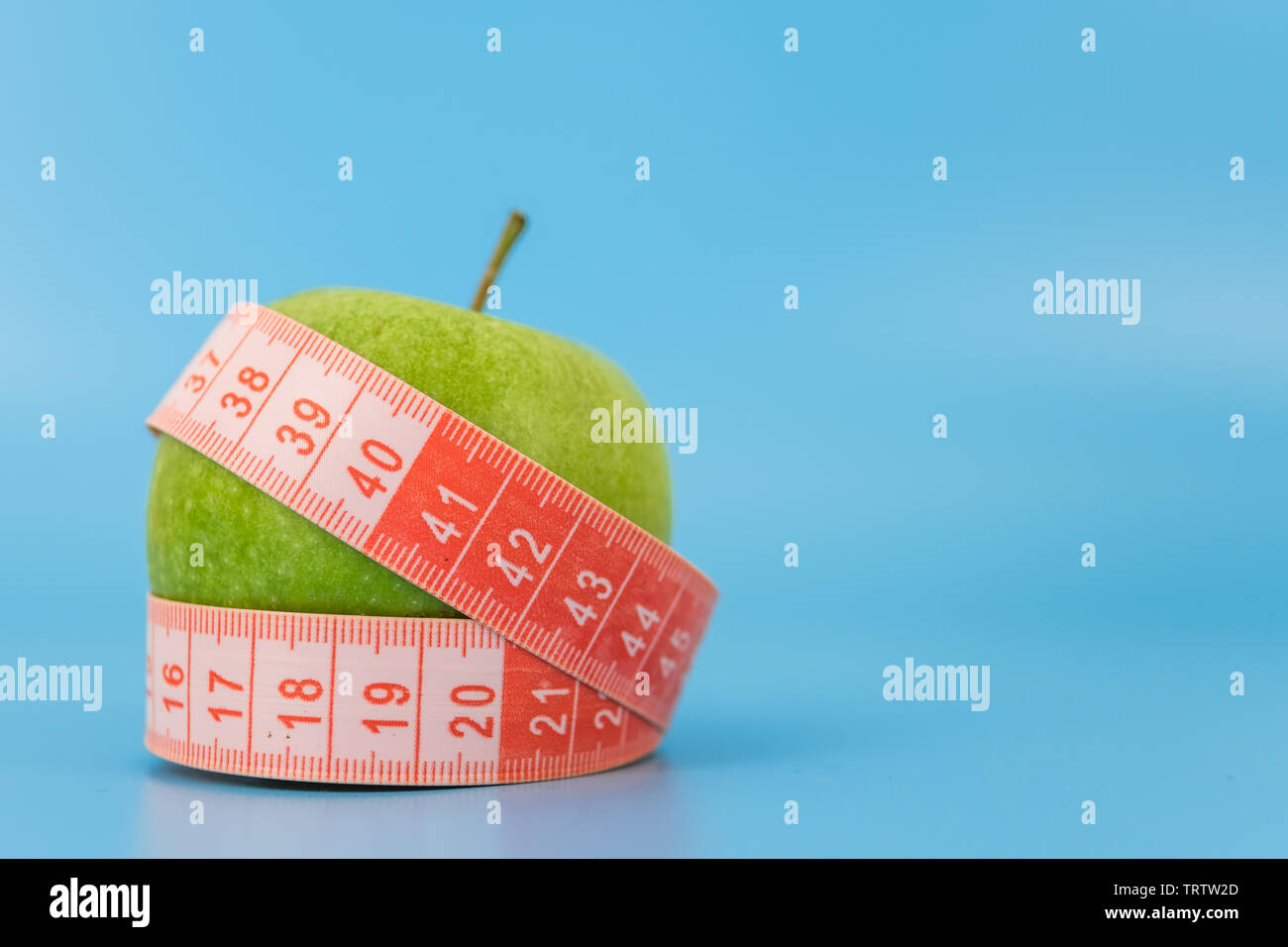 red measuring tape with an apple in the background. concept of excess weight and the concept of weight loss. Stock Photo