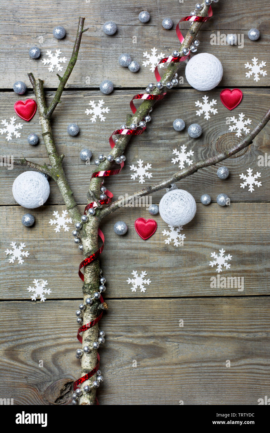 Original christmas tree concept with white cotton baubles, leafless tree branches, hearts, snow flakes and silver bead chain on wooden background Stock Photo