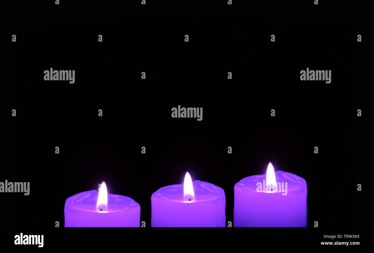 Shining three purple candles on black background with copy space Stock