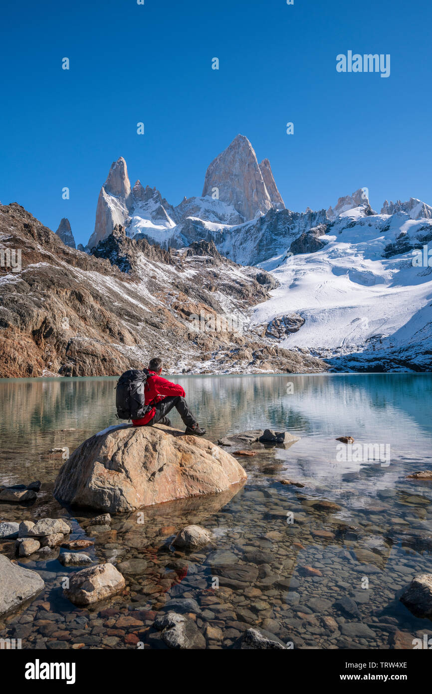 Walker sat admiring the view of  Mt Fitz Roy and Cerro Torre with Lago de los Tres, El Chalten, Patagonia, Argentina. Stock Photo