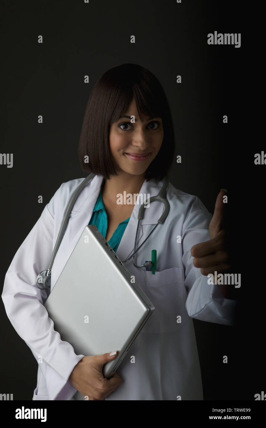 Indian female doctor holding a laptop and giving thumbs up Stock Photo ...