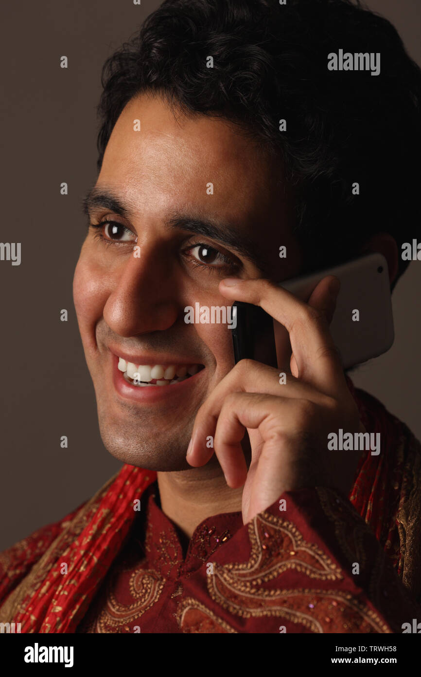 Indian man talking on a mobile phone and smiling Stock Photo - Alamy