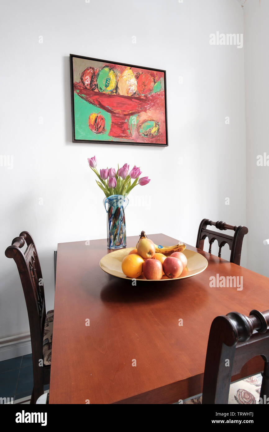 Kitchen dining table with three empty chairs, fruit bowl and still-life painting on the wall, Berlin, Germany Stock Photo