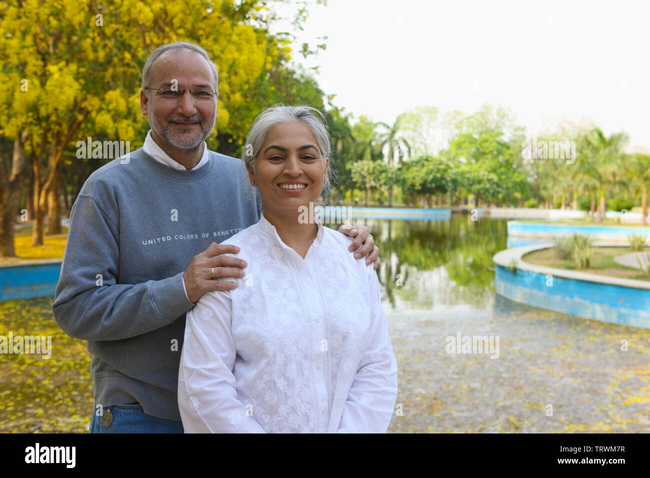 Couple standing in a park and smiling Stock Photo - Alamy