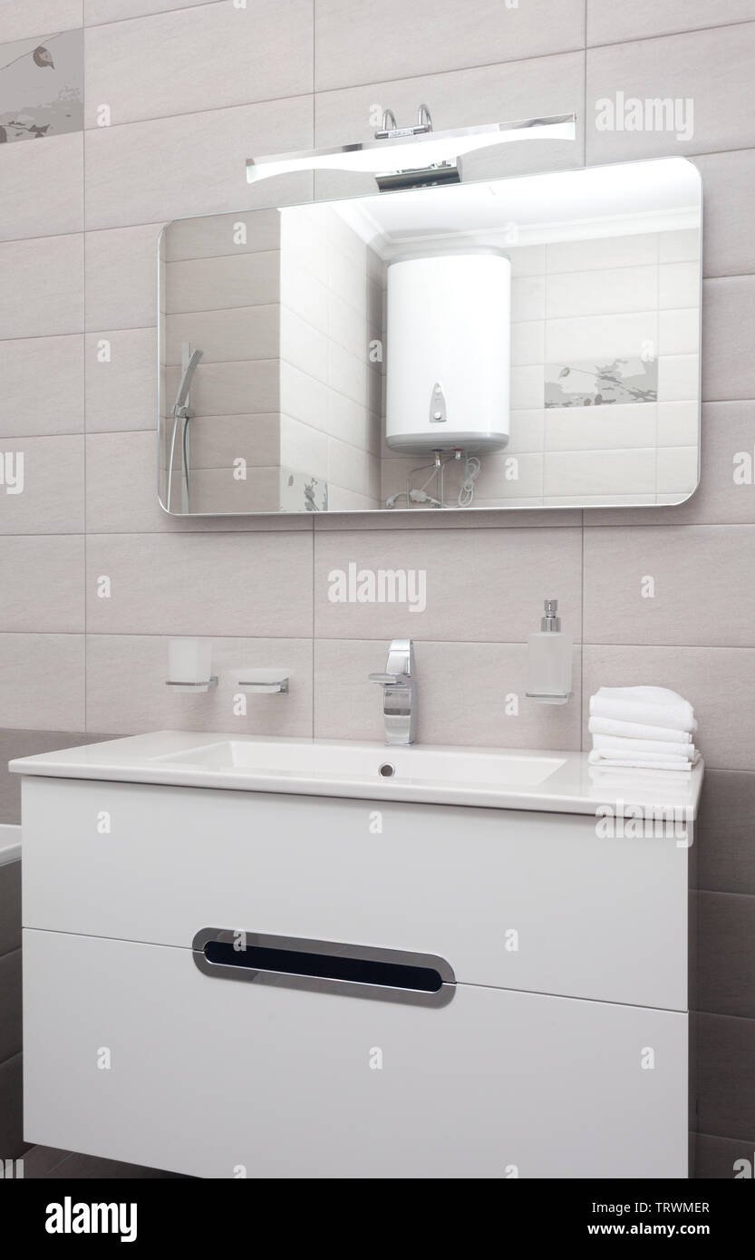 epmty minimalistic interior background, bathroom of modern apartment, closeup of mirror, tap and basin in light colors, nobody, with copy space, verti Stock Photo