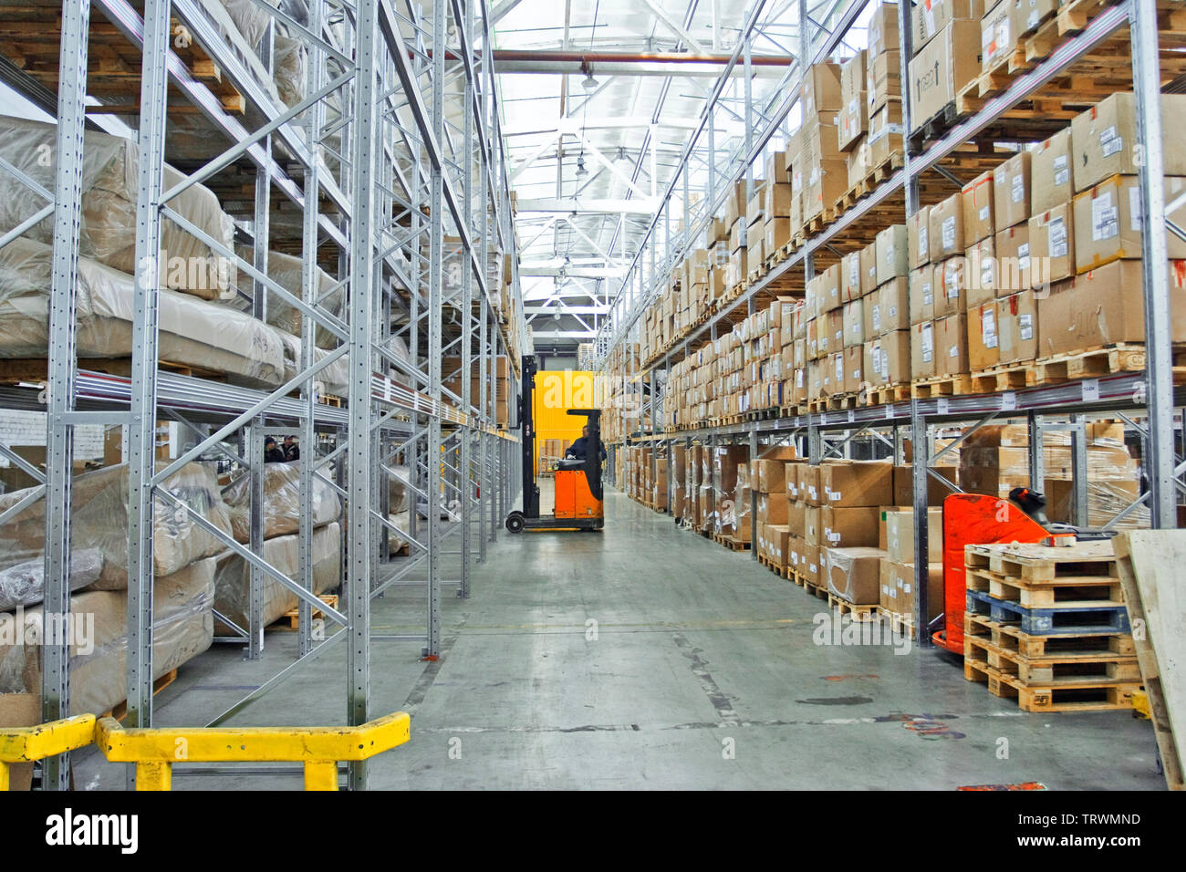large modern empty warehouse, industrial interior with forklifts. rows of shelves with pallets, boxes, containers and goods Stock Photo