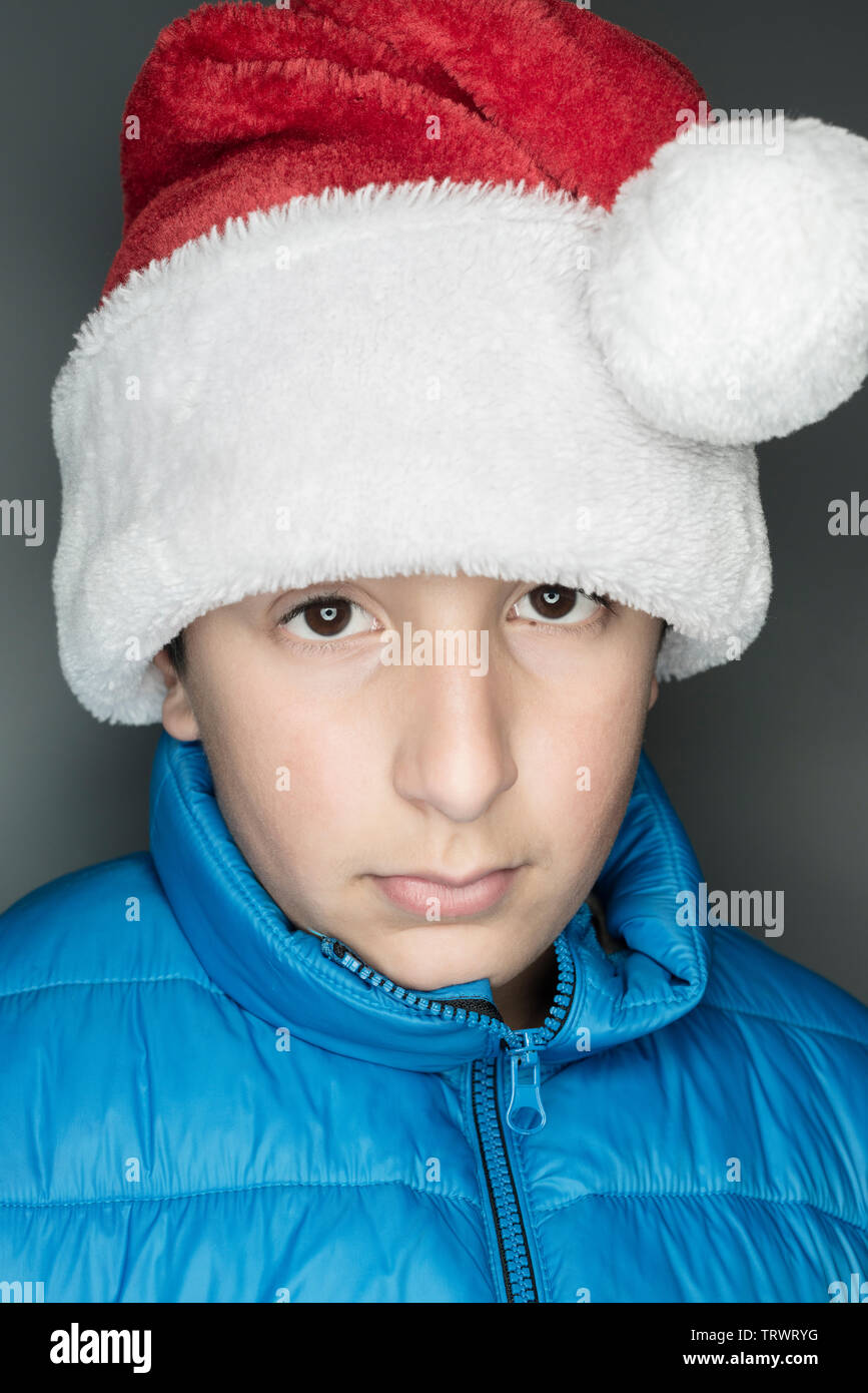 11 years old Caucasian boy in bblue jacket and Santa's hat Stock Photo