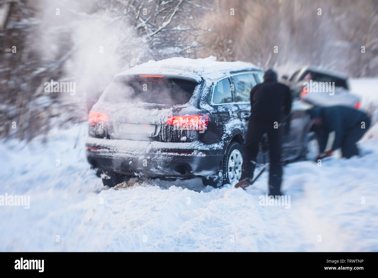 Process of taking out suv car stuck in snow, men digging and pushing the car out of snow