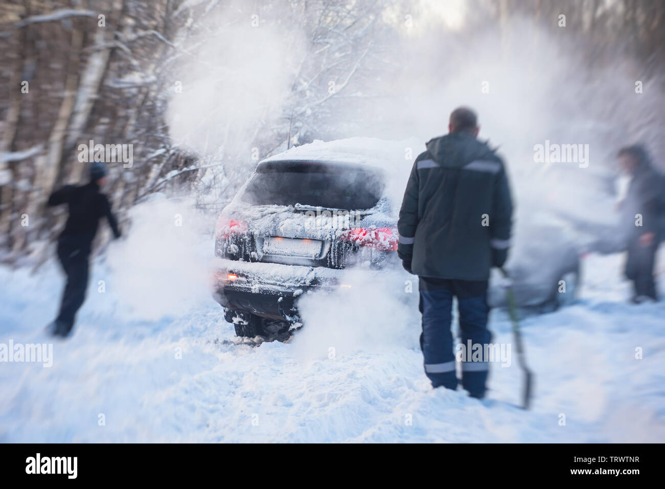 Process of taking out suv car stuck in snow, men digging and pushing the car out of snow