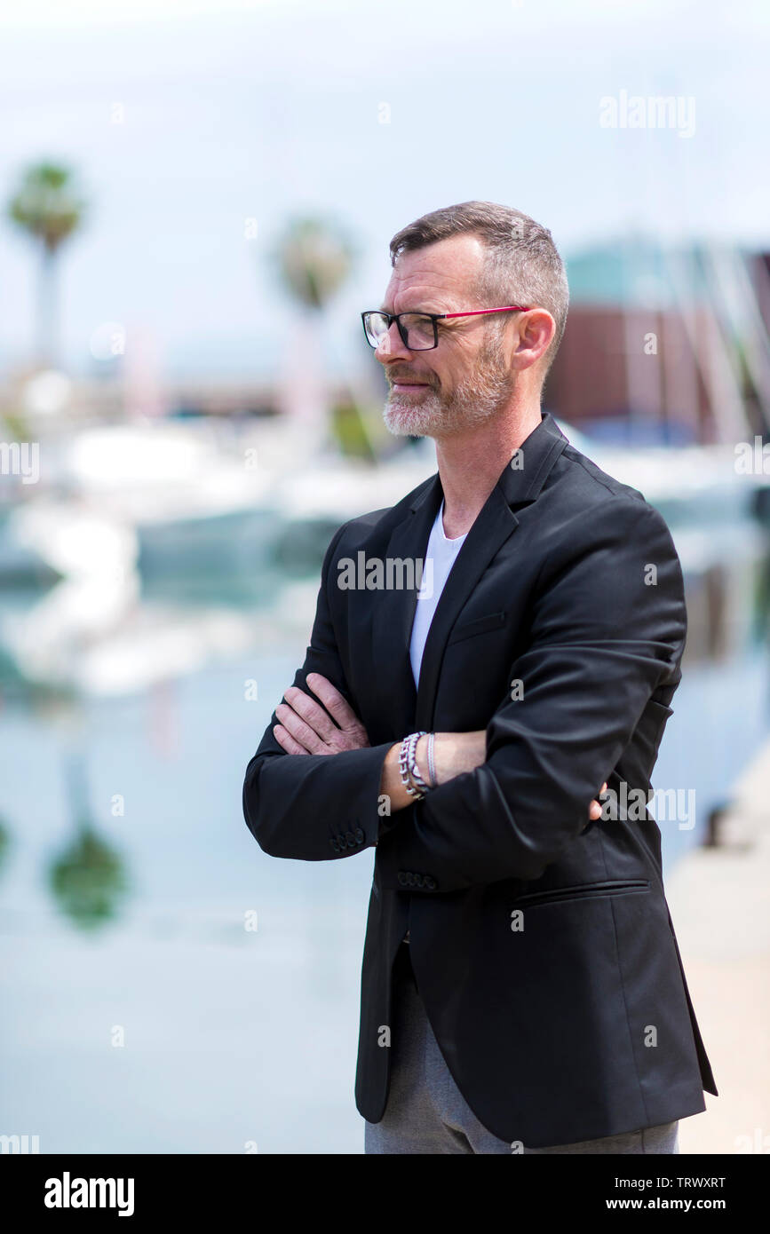 Businessman standing in the city arms crossed while looking away and smiling Stock Photo