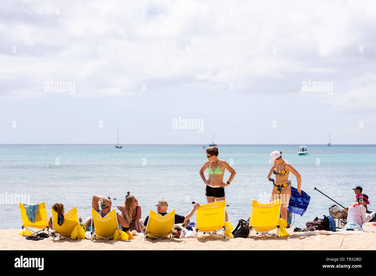 A group of people at the beach, laying out on beach chairs; Waikiki