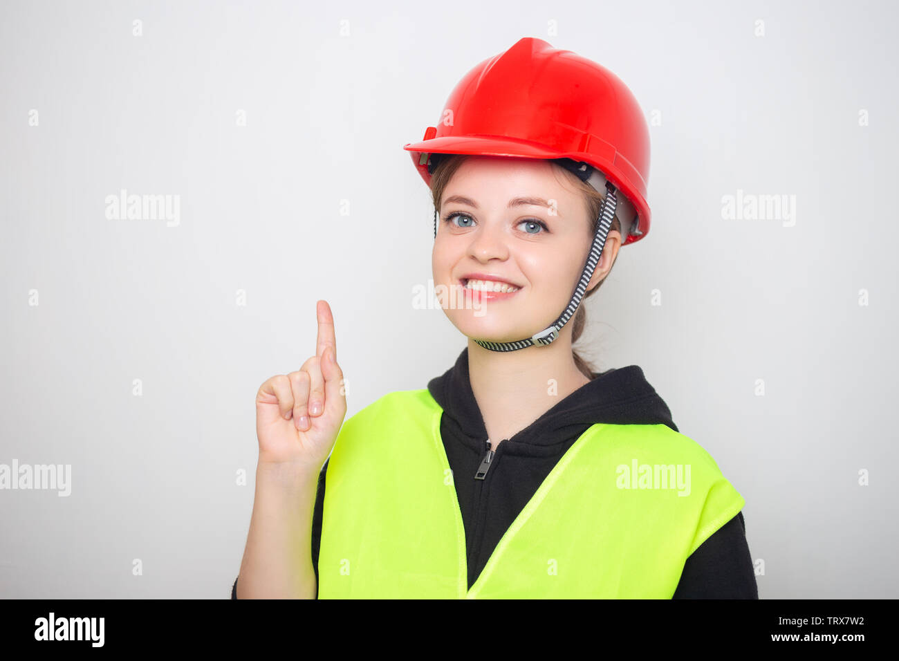 Young caucasian woman wearing red safety hard hat and reflective vest, smiling Stock Photo