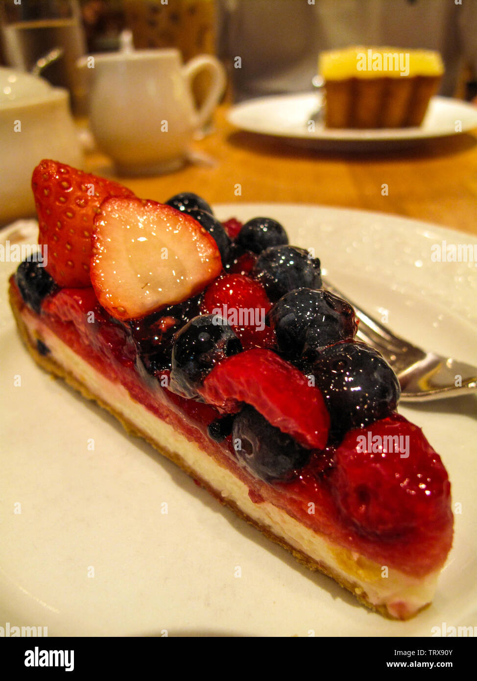 Cheesecake topped with lots of fresh strawberries, raspberries and blueberries in a cafe. Stock Photo