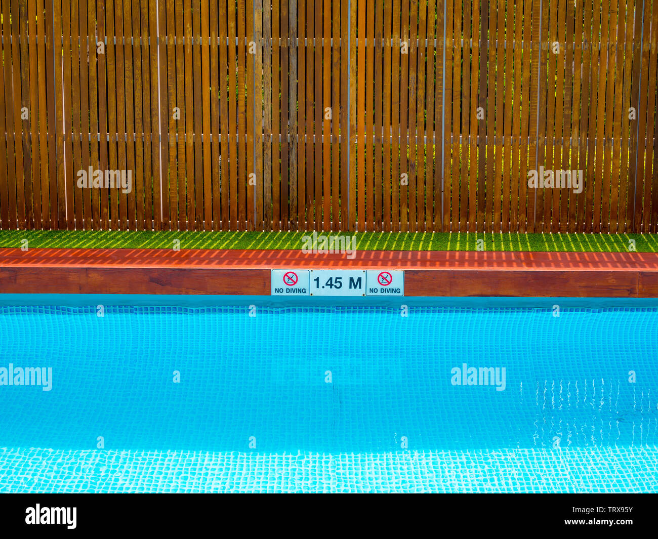 No diving sign and pool depth sign on pool edge on outdoor swimming