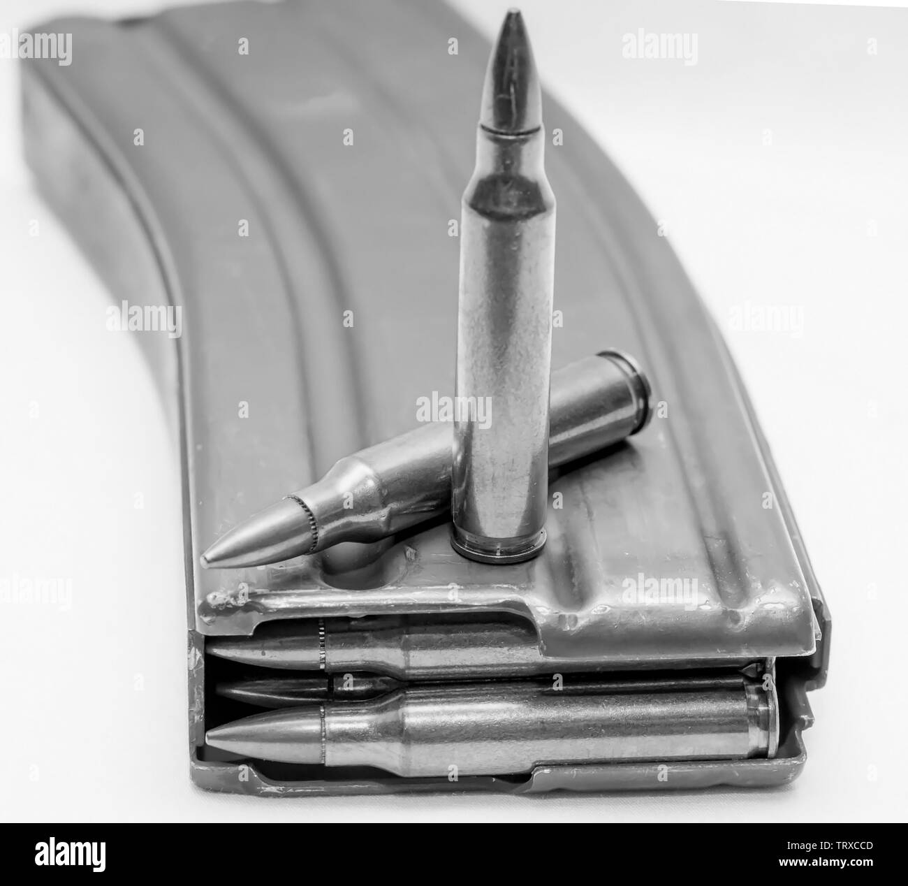 223 caliber bullets loaded into a rifle magazine with two additional bullets shot in black and white Stock Photo