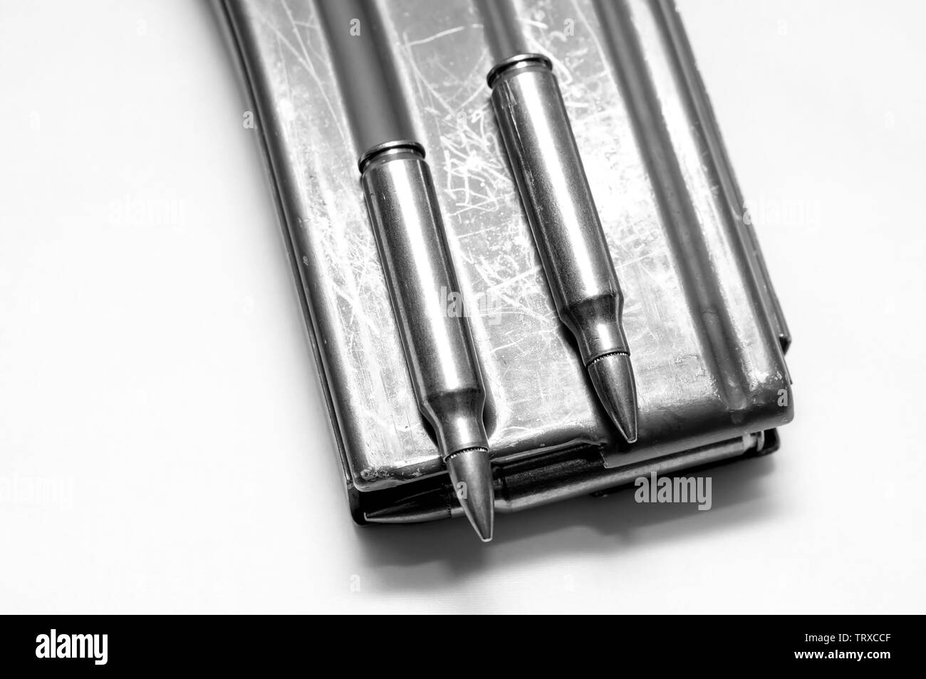 223 caliber bullets loaded into a rifle magazine with two additional bullets shot in black and white Stock Photo