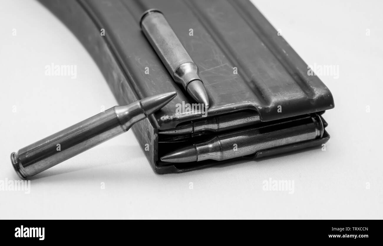 223 caliber bullets loaded into a rifle magazine with two additional bullets shot in black and white Stock Photo