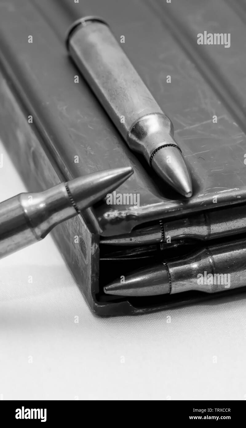 223 caliber bullets loaded into a rifle magazine with two additional bullets shot in black and white Stock Photo
