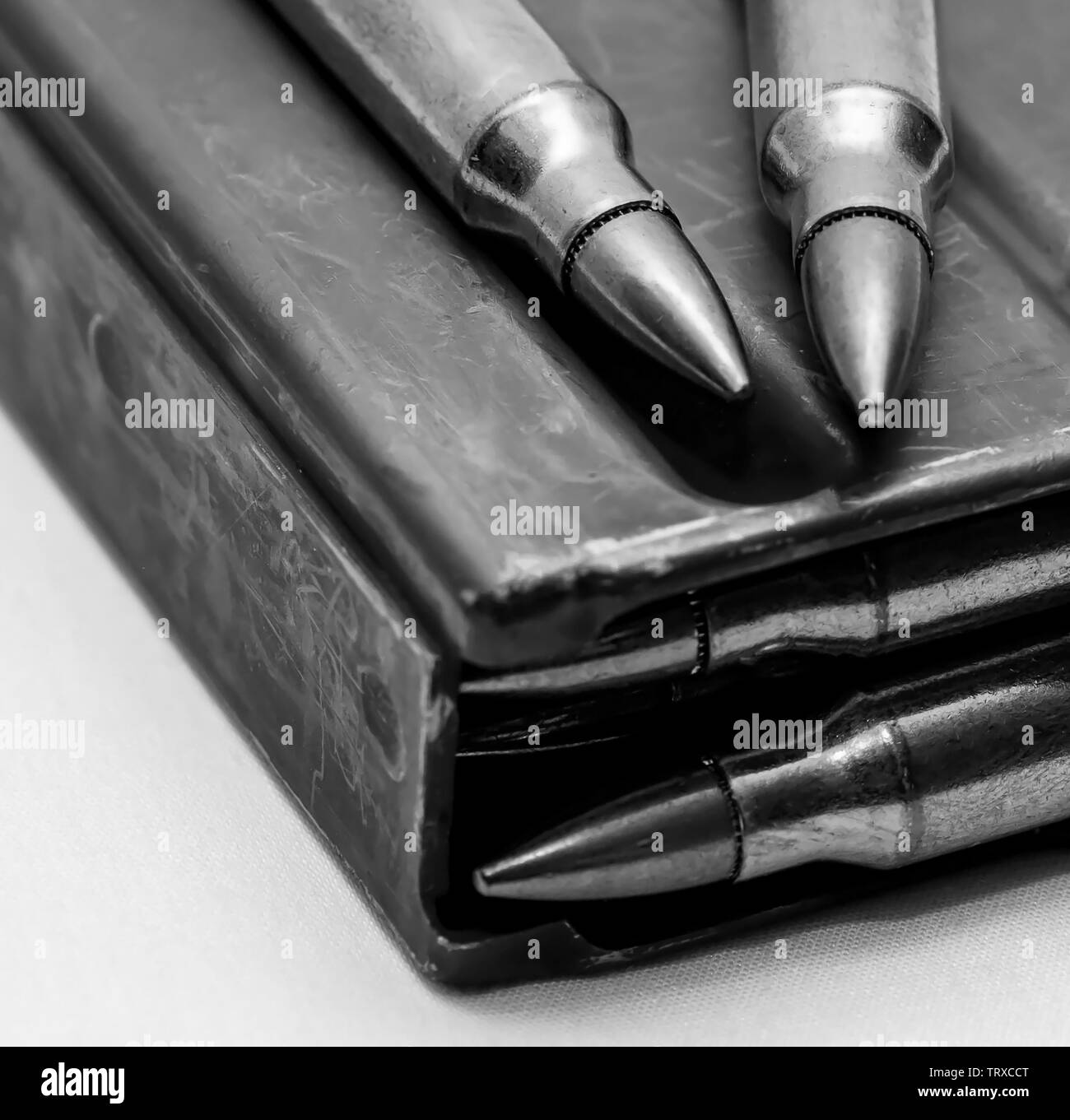 223 caliber bullets loaded into a rifle magazine with two additional bullets shot in black and white Stock Photo