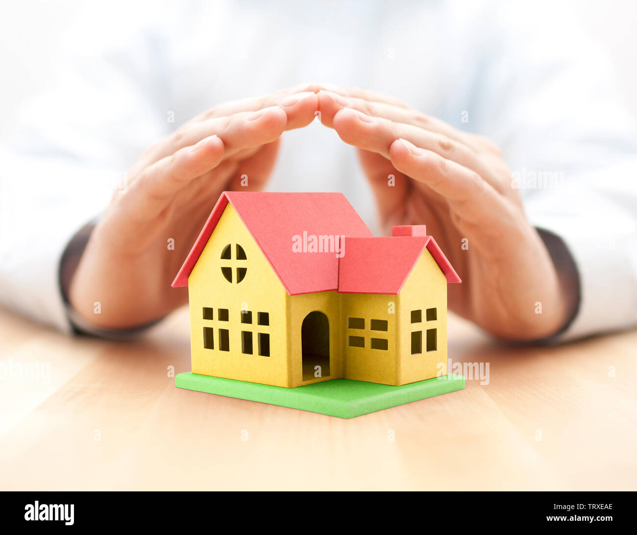 Colorful toy house covered by hands Stock Photo