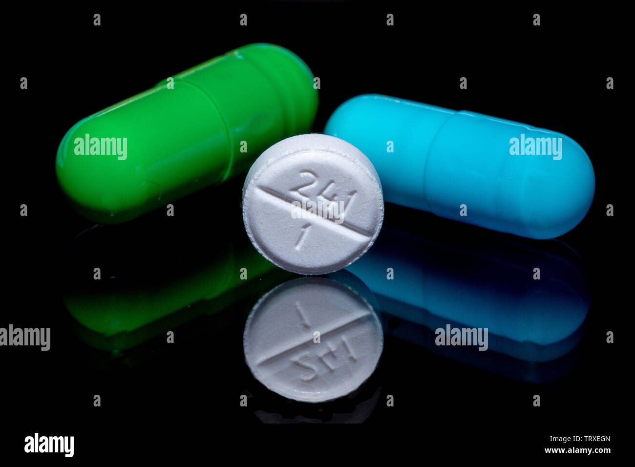 Macro Image of a green pill, blue pill, and a white pill on a ...