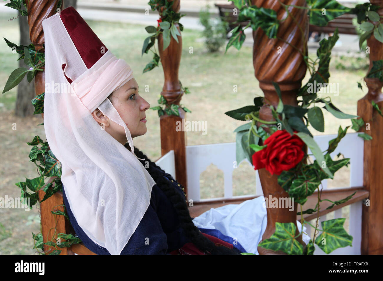 Woman wearing traditional clothes of the Ottoman Empire sitting sitting in a gazebo covered with flowers during the Moscow historical festival Stock Photo