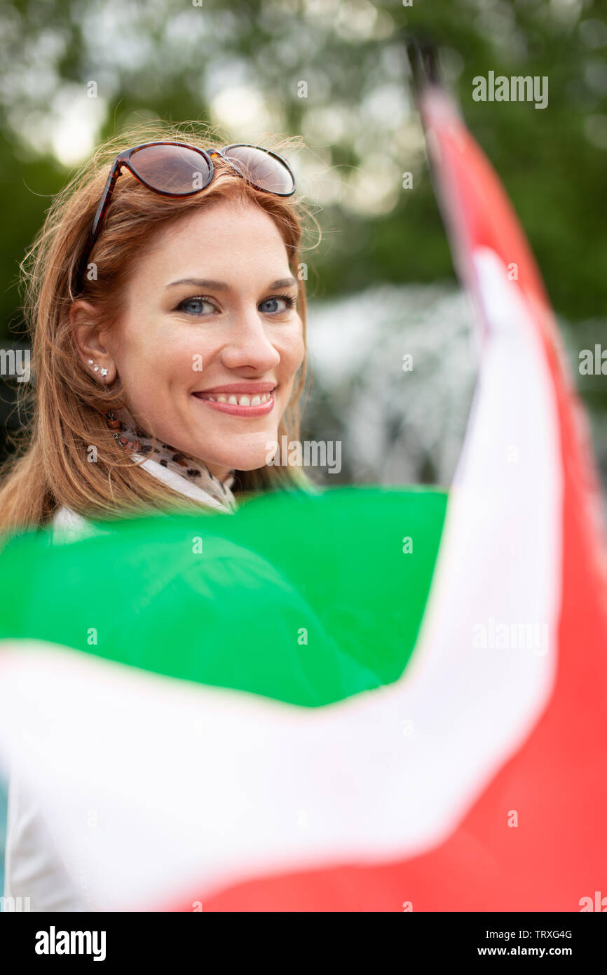 Happy young natural woman with smile holding Hungarian flag, depth of field Stock Photo