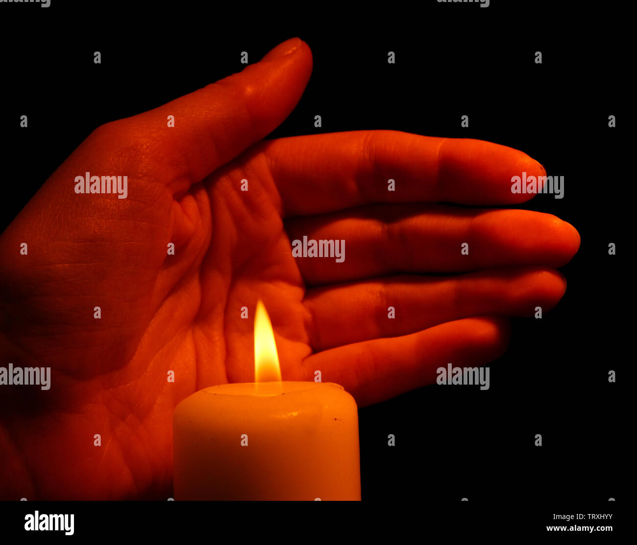 Burning candle and hand isolated on black Stock Photo