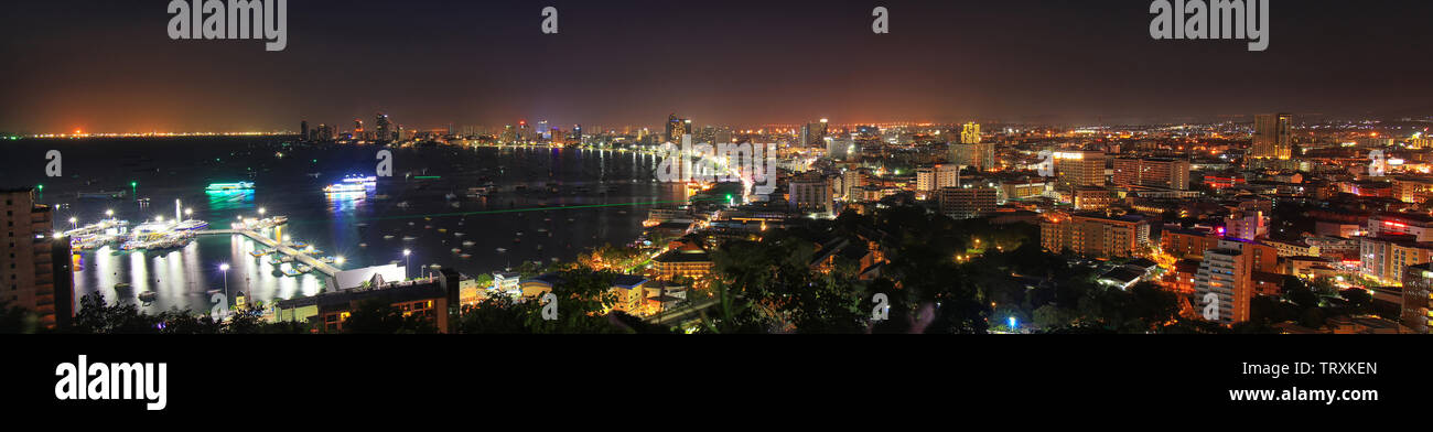 panorama view of pattaya city bay view with building and city night light , boat at dock port. night scene of pattaya city from view point Stock Photo
