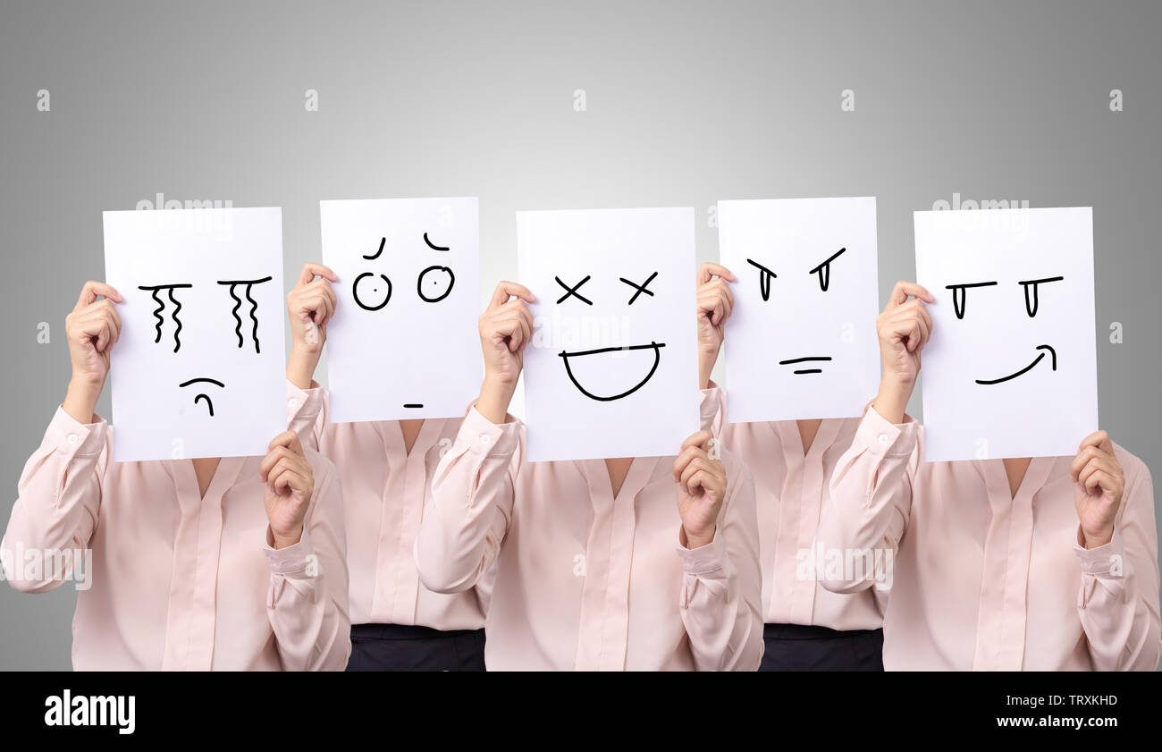 five businesswoman holding a card with drawing facial expressions different emotion feelings face on white paper Stock Photo