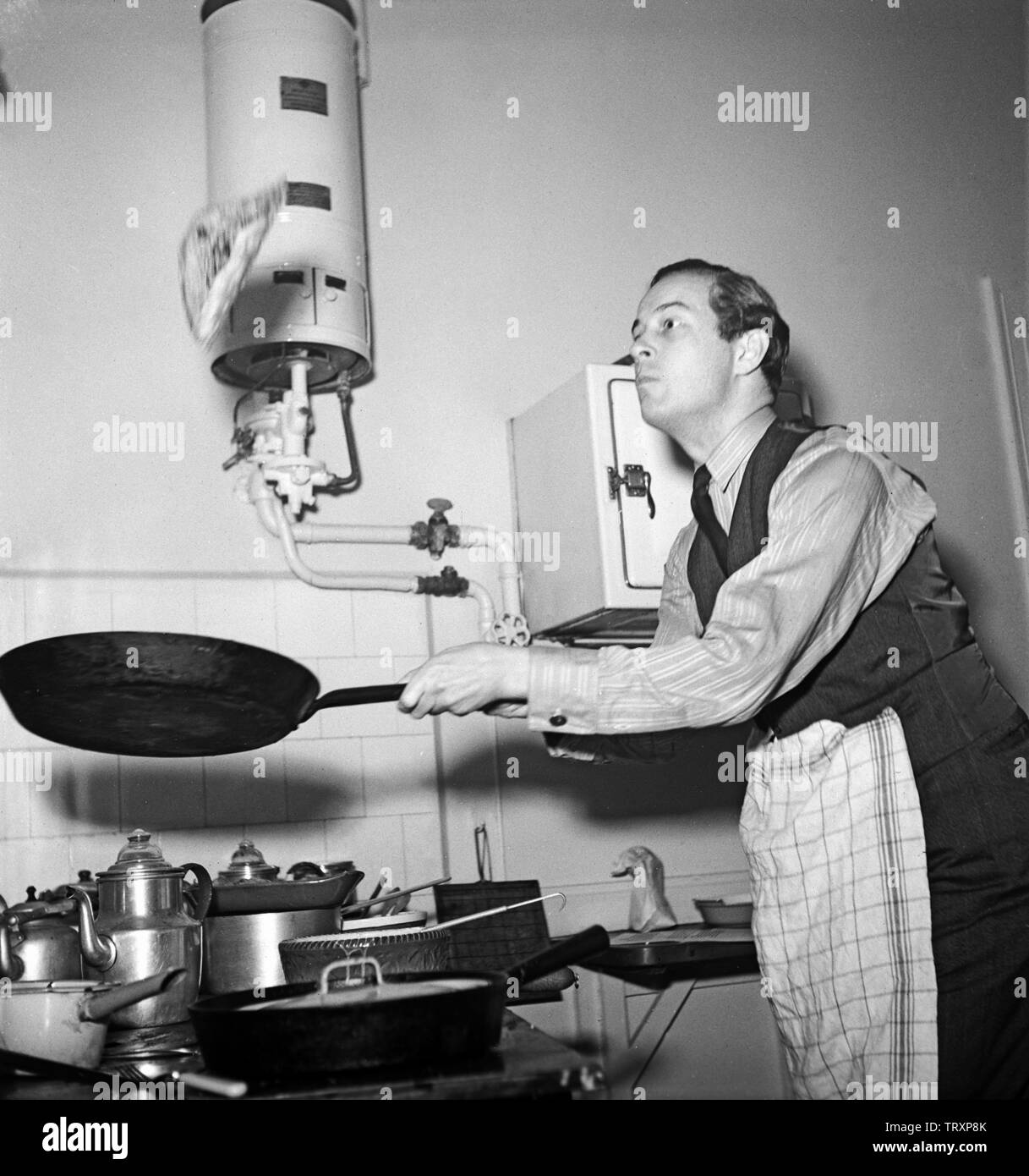 Man of the 1940s. A man is making pancakes and throws it up in the air and hopes it lands again on the other side in the frying pan. Sweden 1945 Kristoffersson Ref R84-1 Stock Photo