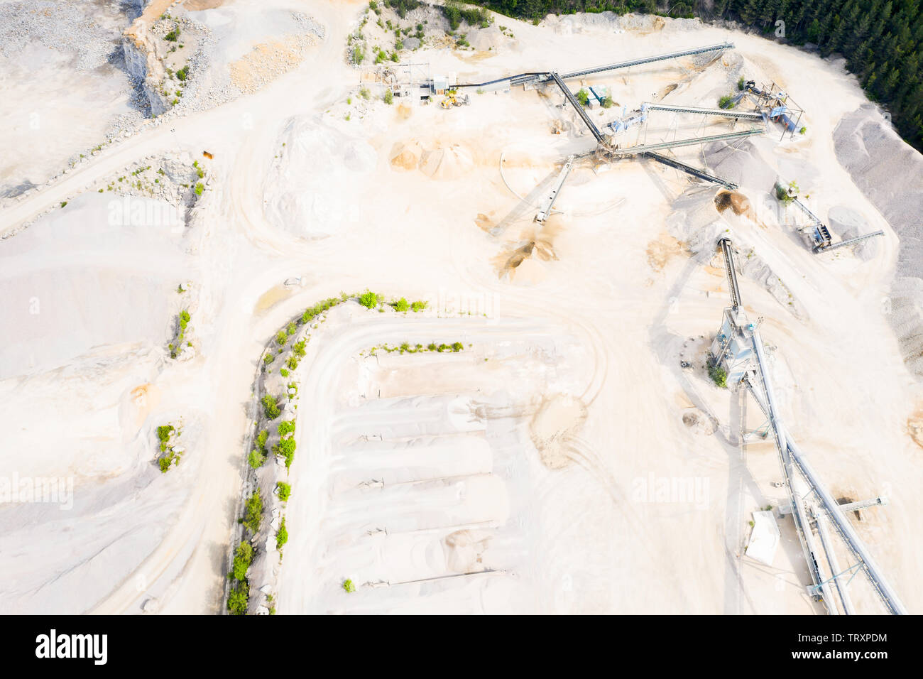 Aerial of stone crushers and sorters in a quarry landscape. Heaps of gravel and stones in the pit and many conveyor belts radiating out from the crush Stock Photo
