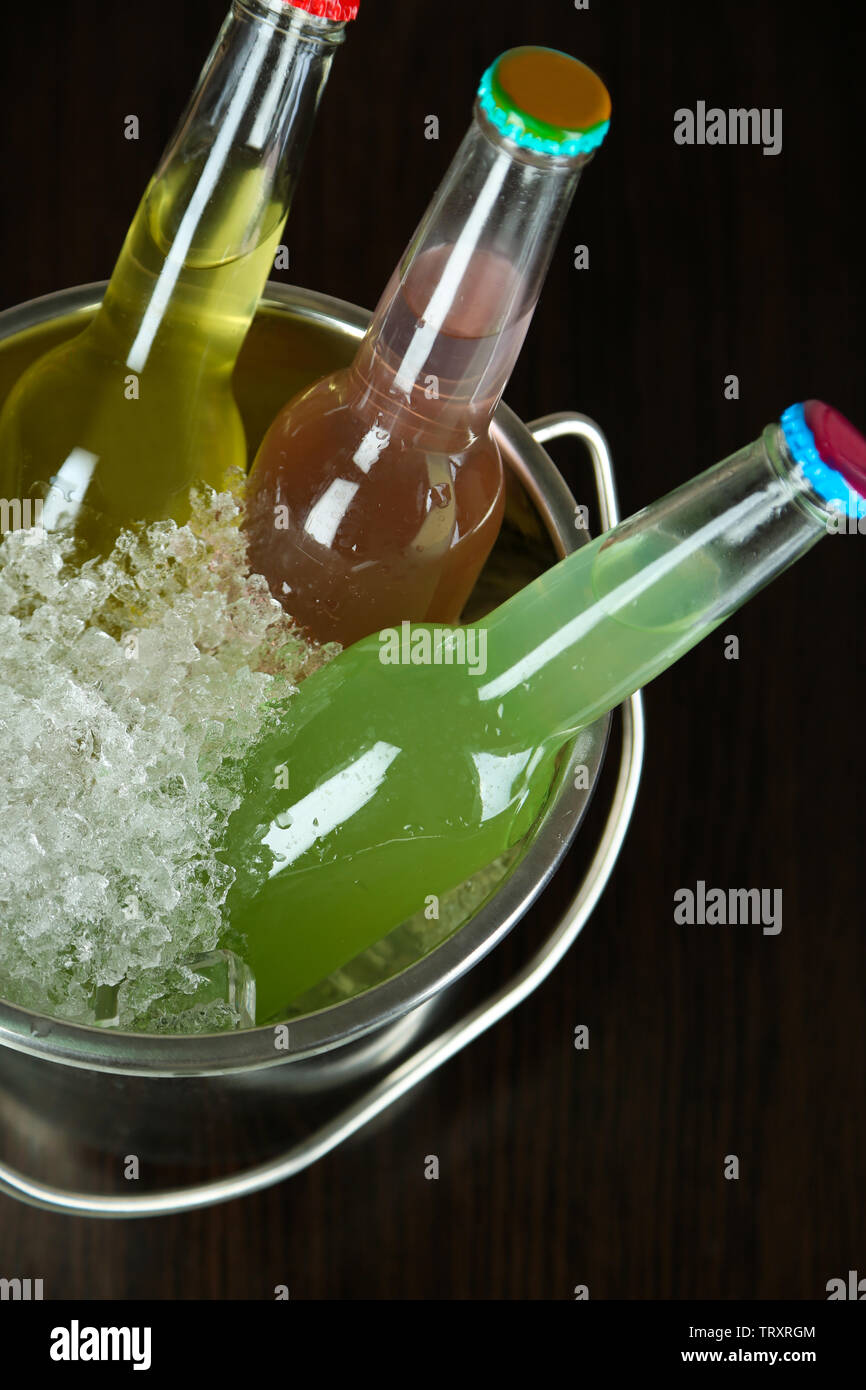 Bottled drinks in ice bucket on brown background Stock Photo