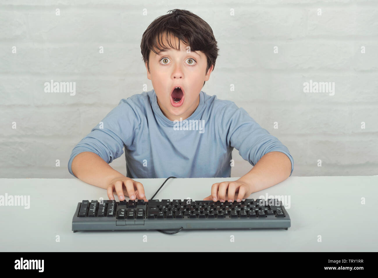 surprised child with keyboard on brick background Stock Photo