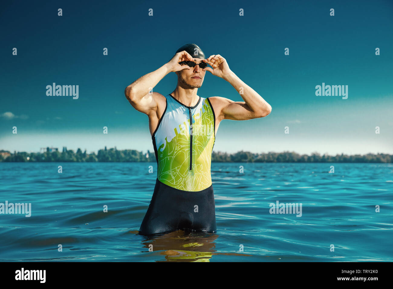 Professional triathlete swimming in river's open water. Man wearing swim equipment practicing